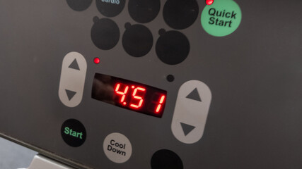 Close-up of an illuminated treadmill control panel showing 4:51 countdown timer, ideal for fitness and gym workout concepts