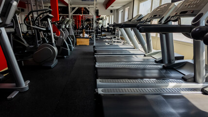 Empty modern gym with rows of treadmills and exercise machines, emphasizing wellness and fitness goals