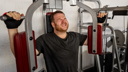 Caucasian man straining on gym equipment, symbolizing the struggle and determination in fitness...