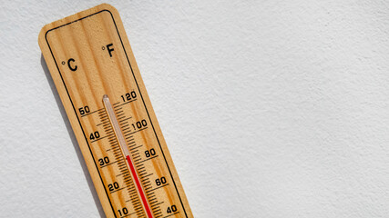 Wooden thermometer displaying high temperature in Celsius and Fahrenheit, representing heatwave and...