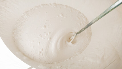 A close-up of white paint being mixed in a bucket, representing home renovation and DIY projects