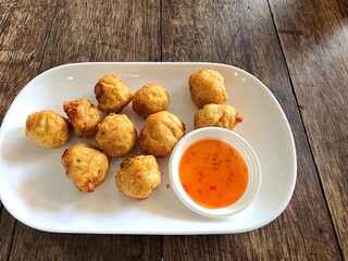 Deep fried shrimp ball served on a white plate with sweet and spicy dipping sauce. It is a popular appetizer in noodle shops. Minced shrimp mixed with various seasonings, steamed and fried in oil.
