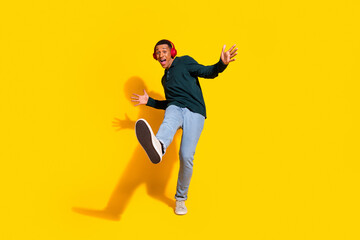 Full length photo of attractive young man headphones dance have fun dressed stylish green clothes isolated on yellow color background