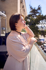 plus size woman in peach fuzz dress on terrace overlooking church