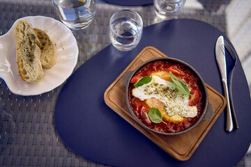 medium sized woman in peach fuzz dress eating Shakshouka in modern restaurant