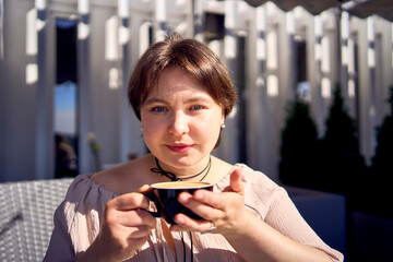 a medium sized woman in peach fuzz dress with cup of coffee in coffee shop in morning light