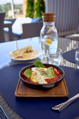 medium sized woman in peach fuzz dress eating Shakshouka in modern restaurant