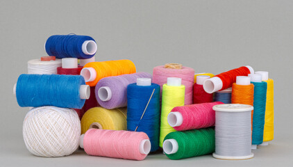 Colorful thread spools on grey background.