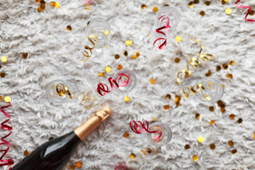 Obraz premium a bottle of champagne and glasses for champagne for christmas, new year, party, wedding celebration with gold red confetti and decoration