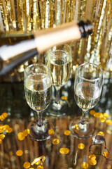 a bottle of champagne and glasses for champagne for christmas, new year, party, wedding celebration with gold red confetti and decoration