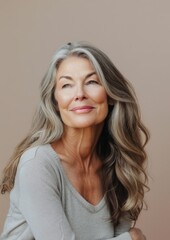 Fototapeta premium A graceful portrait of a mature woman, her smile subtle yet captivating with a light pink background.