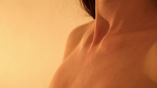 Beautiful female neck and breast close-up in soft light. Naked woman's body part. Thyroid gland. Copy space. Skin care. Fossa jugularis. Tender clavicles. Pleasure concept. 4K