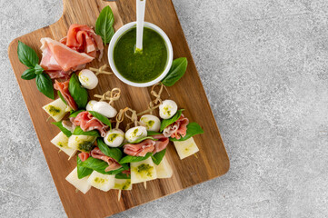 Appetizer with melon, mozzarella, prosciutto ham and fresh basil on stick with pesto sauce on a...