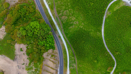 A beautiful bike path shot from above. Flying a quadcopter over a bike path. Green grass and bushes near the beach in the Netherlands. Sand dunes. Beautiful flight in summer over the beach.