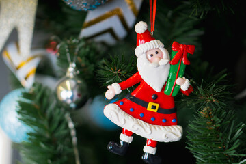 A colorful santa claus ornament is beautifully hanging from the christmas tree
