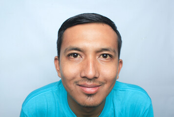 Close up Asian young man wearing blue t-shirt smile and looking into the camera.