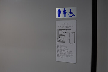 Toilet location sign with diagram of restroom in braille text for person who has lost vision,...