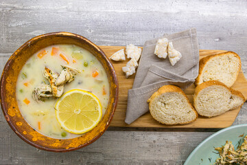 Italian Cuisine Concepts. Clay Bowl of Italian Lemon Chicken Orzo Soup With Loafs of Dark and White...