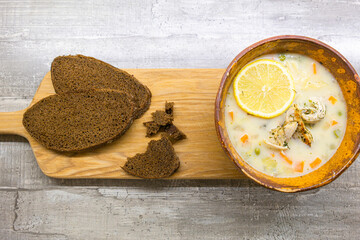 Italian Cuisine. Brown Clay Bowl WIth Italian Lemon Chicken Orzo Soup With Freshly Baked Dark Bread Over Wooden Background