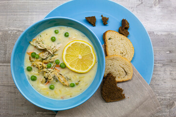 Food Cuisine Concepts. Italian Lemon Chicken Orzo Delicious Soup in Blue Bowl With Napkin Over Wooden Grey Background. Top view.