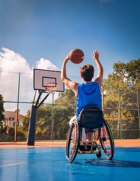 Un adolescente con silla de ruedas practicando baloncesto en una cancha al aire libre; la imagen refleja inclusi&oacute;n, esfuerzo y diversi&oacute;n en una actividad f&iacute;sica.