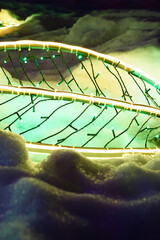 Christmas, New Year LED garland in the form of a tree leaf on snow. Festive vertical template, holiday background with copy space. Neon decorative lighting in winter.