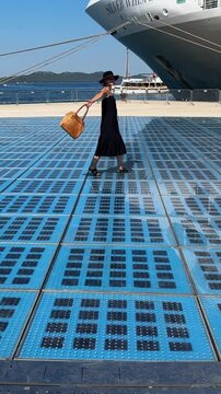 woman dancing on The Greeting to the Sun tourist attraction located on pier in Zadar, Croatia
