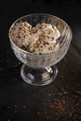 white creamy ice cream with pieces and crumbs of chocolate in a glass bowl