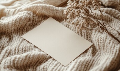 Blank card on a knitted fabric with dried flowers.