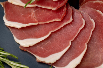 sliced ham with bacon on a board