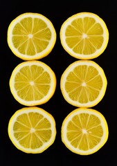 Six lemon slices evenly arranged in two rows on a black background, highlighting their vibrant yellow color and detailed textures.