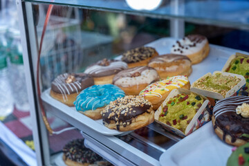 Assortment of Glazed and Topped Donuts in a Glass Display Case
