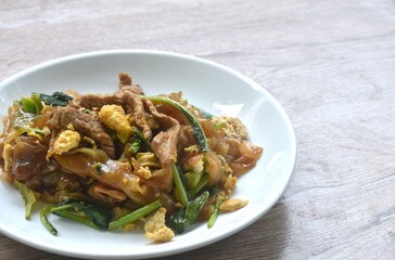 stir fried large rice noodles with slice fermenting pork and Chinese kale dressing black sweet soybean sauce on plate