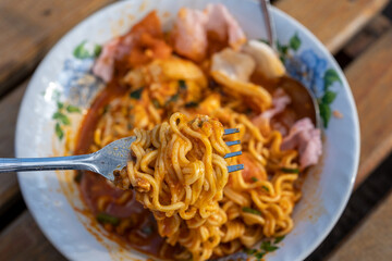 Fork Lifting a Bite of Spicy Noodles with Sauce and Toppings