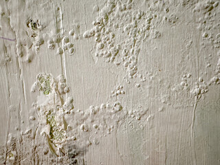 close up view of wall with bubbling paint and cracks, revealing damp spots underneath. The surface...