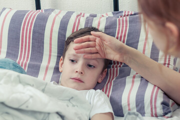 A mother measures the temperature of a sick child, carefully supporting him at the time