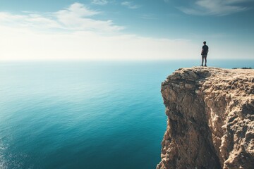 A lone man stands at the brink of a cliff, peering out over a tranquil and expansive ocean stretching to the horizon beneath an airy, light-filled sky, symbolizing introspection and freedom.
