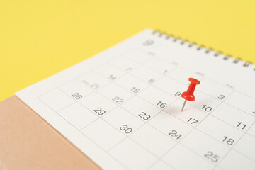 close up of pin on calendar on the yellow table background, planning for business meeting or travel...