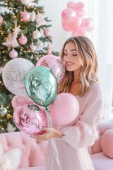 Naklejka premium A joyful woman in a soft pink dress holds festive pink and green balloons beside a beautifully decorated Christmas tree. Christmas and New Year festive concept.