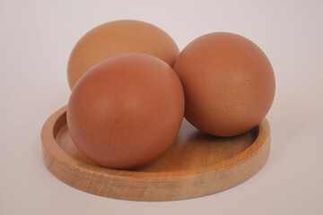 Brown eggs on wooden plate isolated on white background. Eggs are a common ingredient in cooking. Egg protein is a protein that can be absorbed efficiently. Food concept.