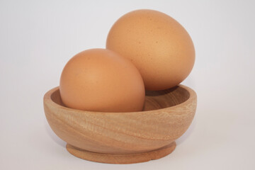 Brown eggs on wooden plate isolated on white background. Eggs are a common ingredient in cooking. Egg protein is a protein that can be absorbed efficiently. Food concept. Modern chicken farming.