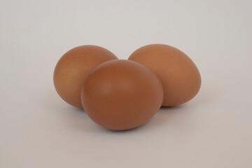 Three brown eggs on wooden plate isolated on white background. Eggs are a common ingredient in cooking. Egg protein is a protein that can be absorbed efficiently. Food concept. Modern chicken farming.