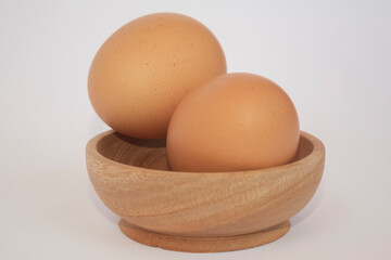Brown eggs on wooden plate isolated on white background. Eggs are a common ingredient in cooking. Egg protein is a protein that can be absorbed efficiently. Food concept. Modern chicken farming.