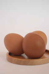 Brown eggs on wooden plate isolated on white background. Eggs are a common ingredient in cooking. Egg protein is a protein that can be absorbed efficiently. Food concept.