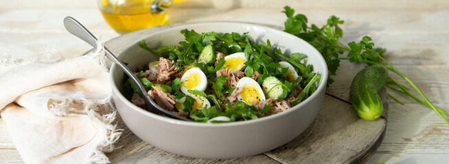 bowl of salad with tuna, cucumber and quail eggs on the table
