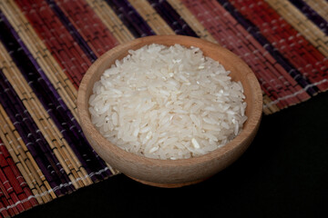 Raw rice in wooden bowl and pile of rice scattered on wooden mat isolated on white background. A group of pure raw rice harvested by farmers. Modern concept style photography of rice in wooden plate.