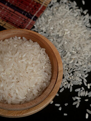 Raw rice in wooden bowl and pile of rice scattered on wooden mat isolated on white background. A group of pure raw rice harvested by farmers. Modern concept style photography of rice in wooden plate.