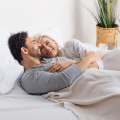 Fototapeta premium Sleeping couple. Blond woman, bearded man lay on home bed in bedroom room - love, relationship, happy family, husband and wife, comfortable or waiting planning child concept image. Square photo.