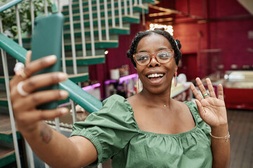 Young African American blogger taking selfie while chilling in cafe