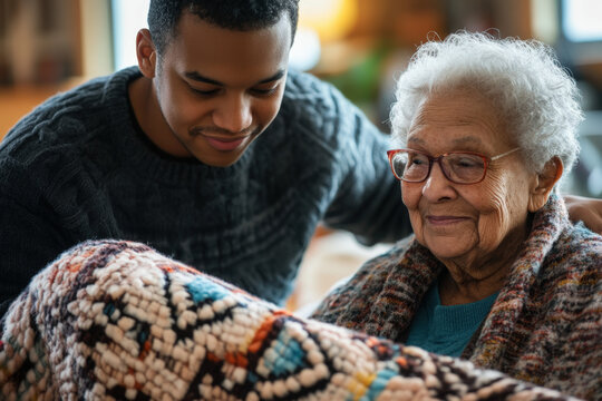 Young volunteer is giving a warm blanket to a smiling senior woman - Powered by Adobe